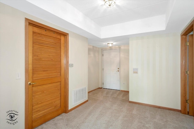 empty room featuring carpet floors, a raised ceiling, visible vents, and baseboards