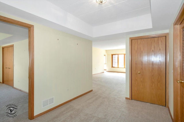 hallway featuring light carpet, visible vents, and baseboards