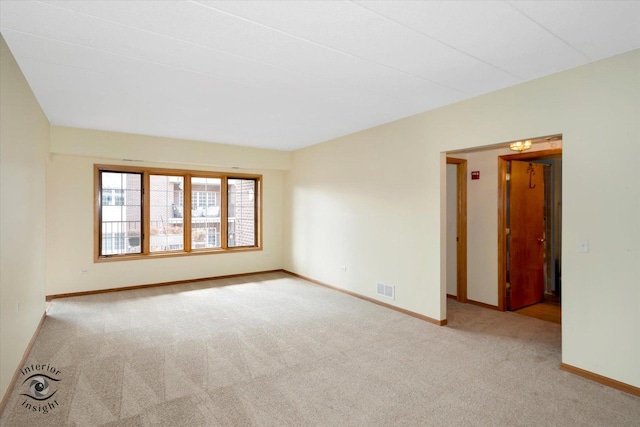 carpeted empty room featuring baseboards and visible vents