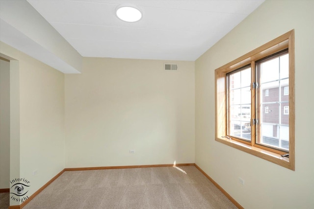 spare room with light colored carpet, visible vents, and baseboards