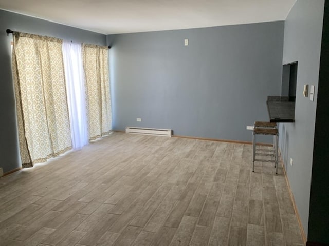 unfurnished living room featuring baseboards, baseboard heating, and wood finished floors