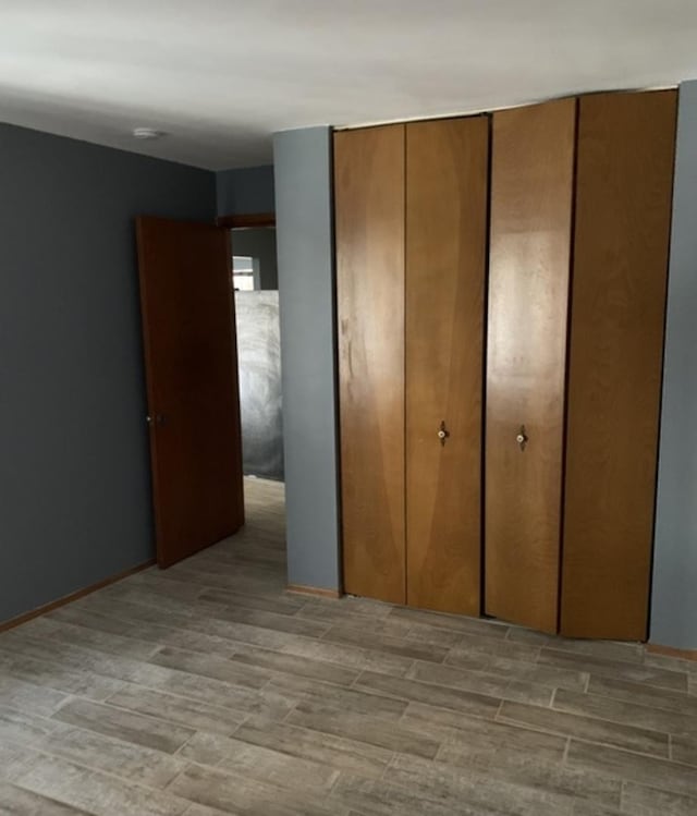 unfurnished bedroom featuring a closet, wood finished floors, and baseboards