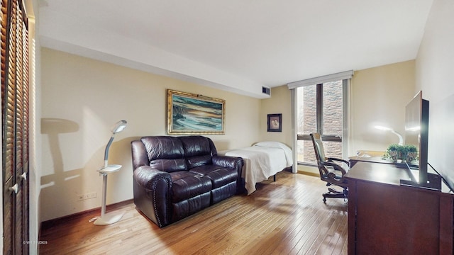 bedroom featuring hardwood / wood-style floors, a wall of windows, visible vents, and baseboards