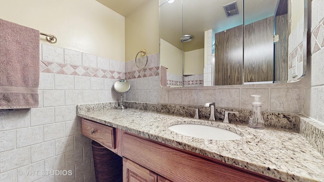 bathroom with visible vents, tile walls, and vanity