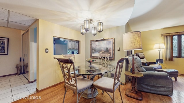 dining space with baseboards, visible vents, a drop ceiling, wood finished floors, and a chandelier