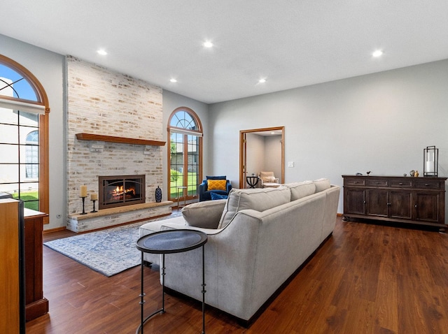 living area featuring a brick fireplace, dark wood-style flooring, and recessed lighting