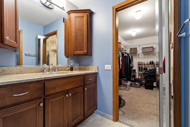 bathroom featuring a walk in closet, vanity, and baseboards