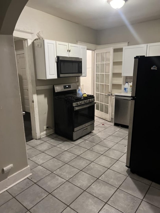 kitchen featuring arched walkways, open shelves, light tile patterned floors, appliances with stainless steel finishes, and white cabinetry