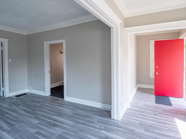 unfurnished room featuring baseboards, wood finished floors, and crown molding