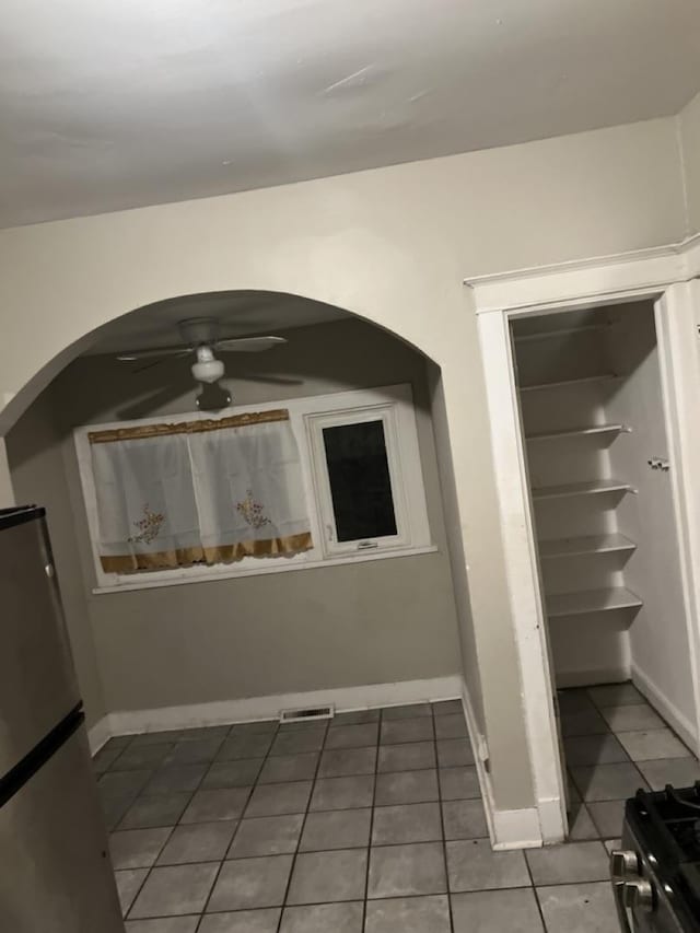 hallway featuring tile patterned flooring, visible vents, arched walkways, and baseboards