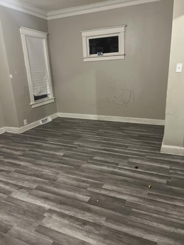 spare room with dark wood-style floors, baseboards, visible vents, and crown molding