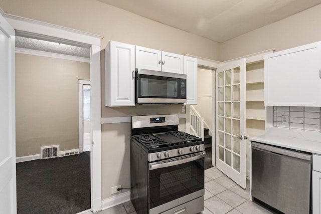 kitchen with stainless steel appliances, visible vents, white cabinets, light countertops, and decorative backsplash