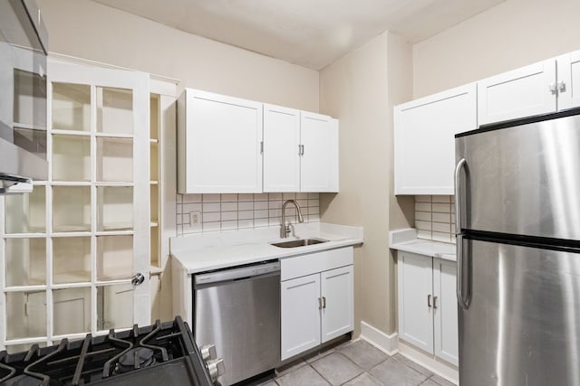 kitchen with white cabinets, a sink, stainless steel appliances, light countertops, and backsplash