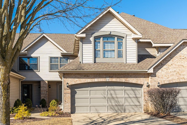 view of front facade featuring driveway, brick siding, and roof with shingles