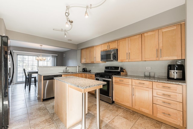 kitchen with appliances with stainless steel finishes, a peninsula, a sink, light brown cabinets, and backsplash