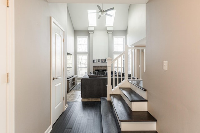 interior space with a towering ceiling, a fireplace, dark wood-style flooring, and a ceiling fan