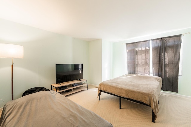 bedroom with baseboards and light colored carpet