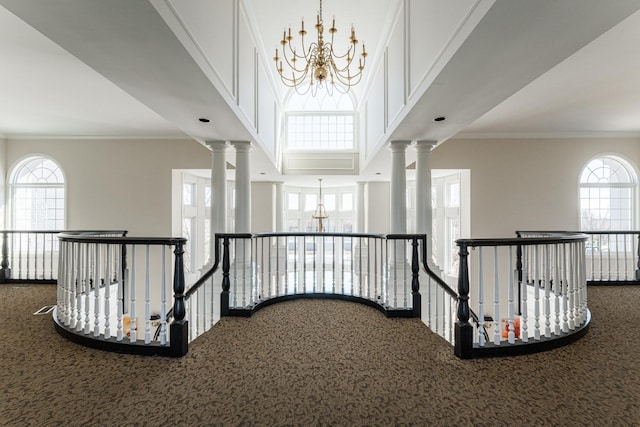 hall featuring an inviting chandelier, crown molding, and an upstairs landing