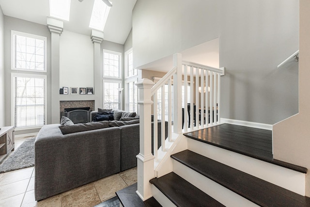 staircase featuring baseboards, a fireplace, and a high ceiling