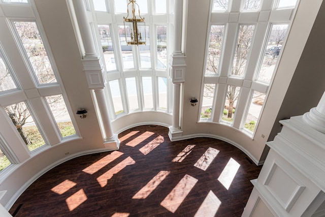 interior details featuring ornate columns, baseboards, a chandelier, and wood finished floors