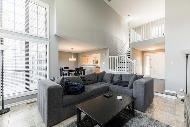 living area featuring plenty of natural light, stairs, visible vents, and baseboards