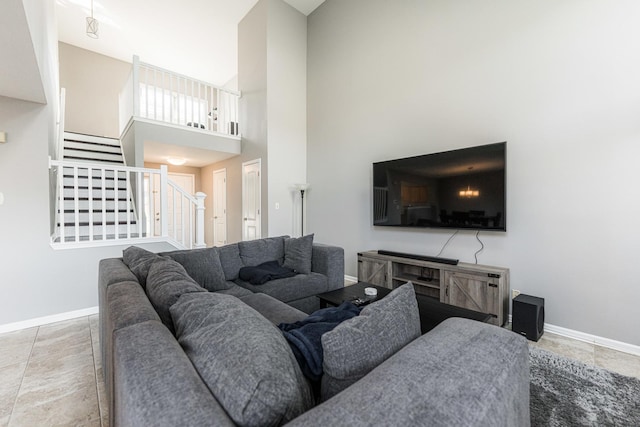 living room featuring a high ceiling, stairway, and baseboards