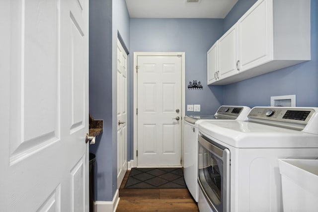 clothes washing area featuring dark wood-style floors, washing machine and clothes dryer, cabinet space, a sink, and baseboards