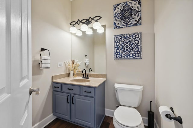 bathroom featuring baseboards, vanity, toilet, and wood finished floors