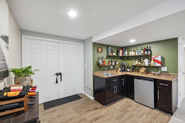 bar with dishwashing machine, light wood-style flooring, a sink, visible vents, and wet bar