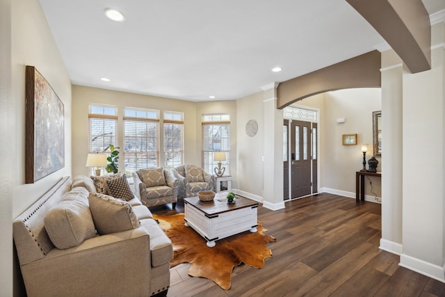 living area featuring dark wood-style floors, arched walkways, baseboards, and recessed lighting