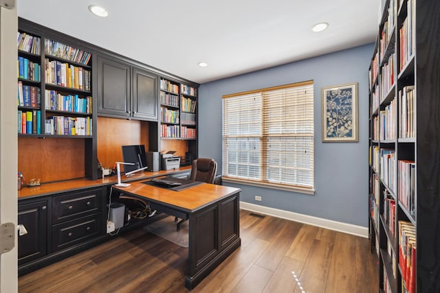 home office with recessed lighting, wood finished floors, visible vents, baseboards, and wall of books