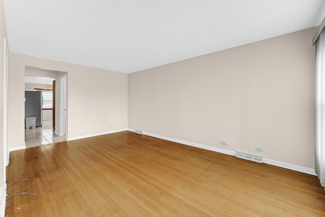 spare room with baseboards, visible vents, and light wood-style floors