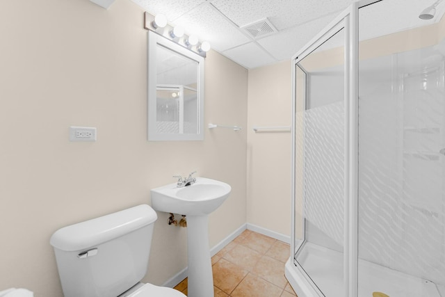 bathroom with a paneled ceiling, visible vents, toilet, a stall shower, and tile patterned floors