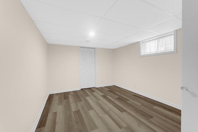 interior space featuring wood finished floors, a paneled ceiling, and baseboards