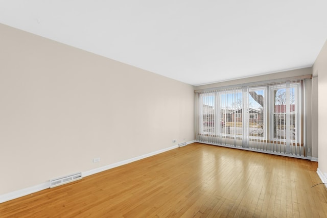 unfurnished room featuring visible vents, light wood-style flooring, and baseboards