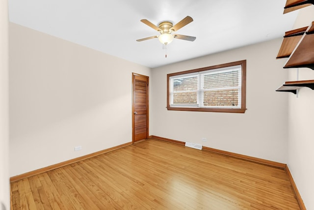 spare room featuring a ceiling fan, light wood-type flooring, visible vents, and baseboards