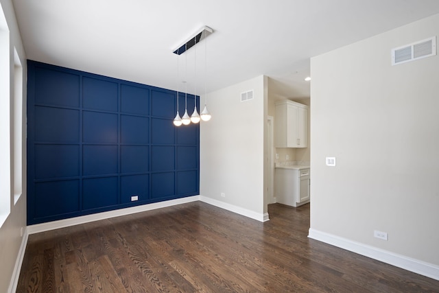 unfurnished room featuring visible vents, dark wood finished floors, and baseboards