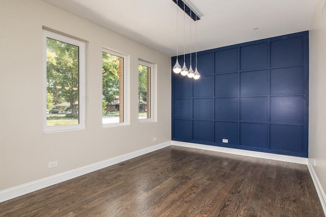 unfurnished room featuring a healthy amount of sunlight, baseboards, and dark wood-type flooring