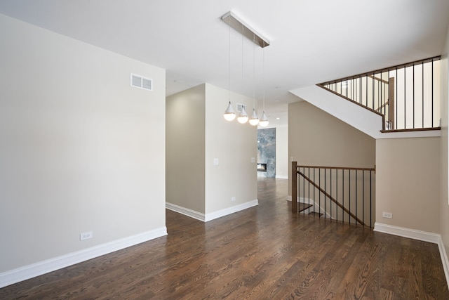 empty room featuring dark wood-type flooring, visible vents, and baseboards