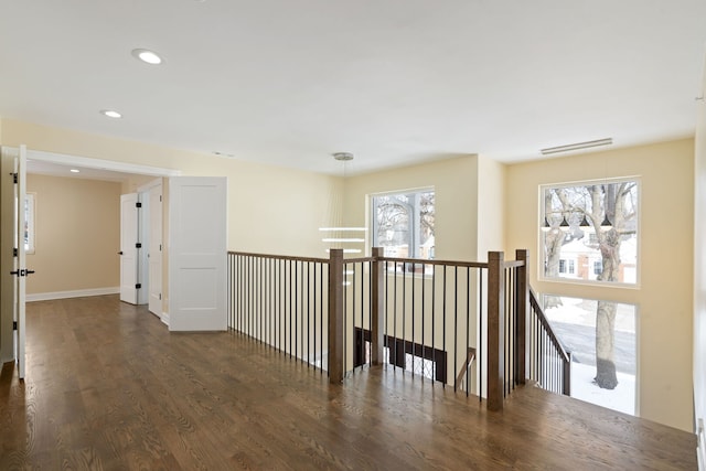 corridor with baseboards, wood finished floors, an upstairs landing, and recessed lighting