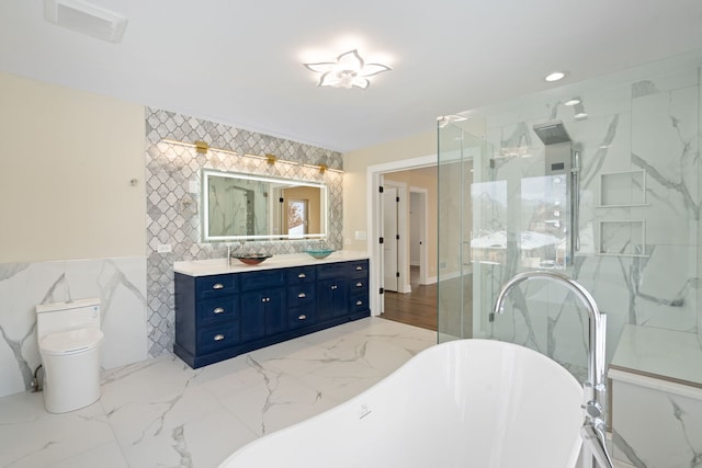 bathroom with marble finish floor, tile walls, a freestanding bath, a stall shower, and vanity