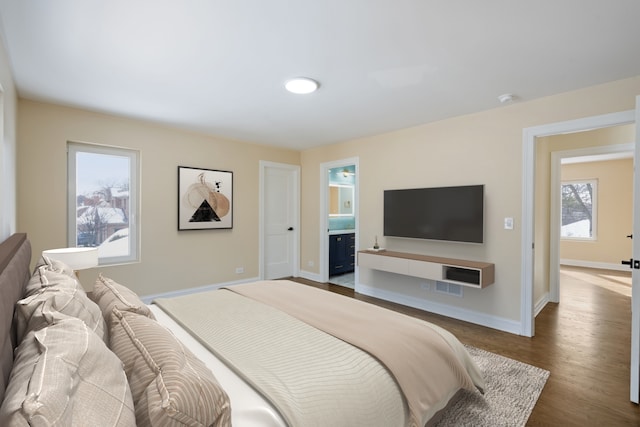 bedroom featuring ensuite bath, baseboards, and dark wood finished floors