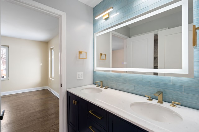 full bath featuring wood finished floors, double vanity, tasteful backsplash, and a sink