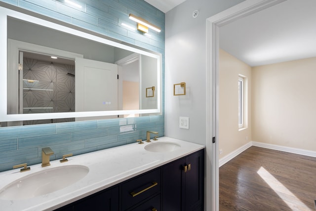 bathroom featuring double vanity, wood finished floors, backsplash, and a sink