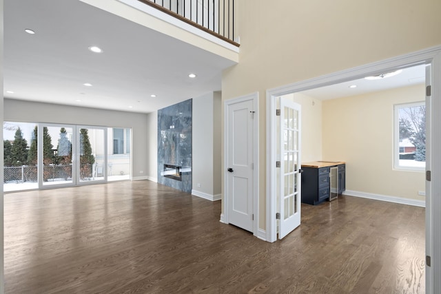 unfurnished living room featuring dark wood-style floors, a healthy amount of sunlight, a fireplace, and baseboards