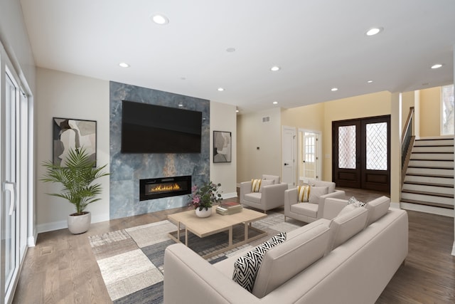 living area with stairway, wood finished floors, french doors, a fireplace, and recessed lighting