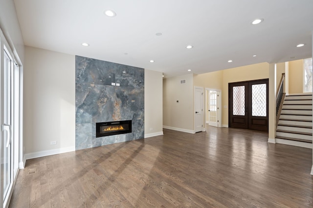 unfurnished living room featuring french doors, recessed lighting, wood finished floors, a tile fireplace, and stairs