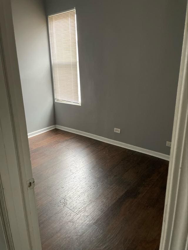 unfurnished room with dark wood-type flooring and baseboards