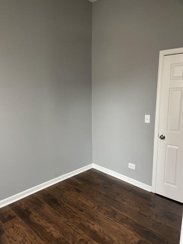 unfurnished room featuring dark wood-style flooring and baseboards