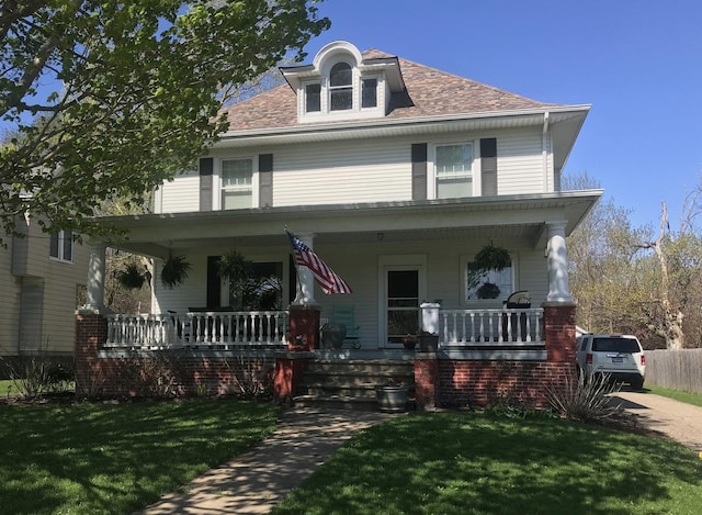 american foursquare style home with a porch and a front yard